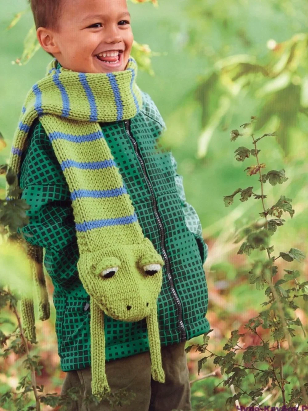 Soft, playful green striped knit scarf with blue accents. Designed with a frog h